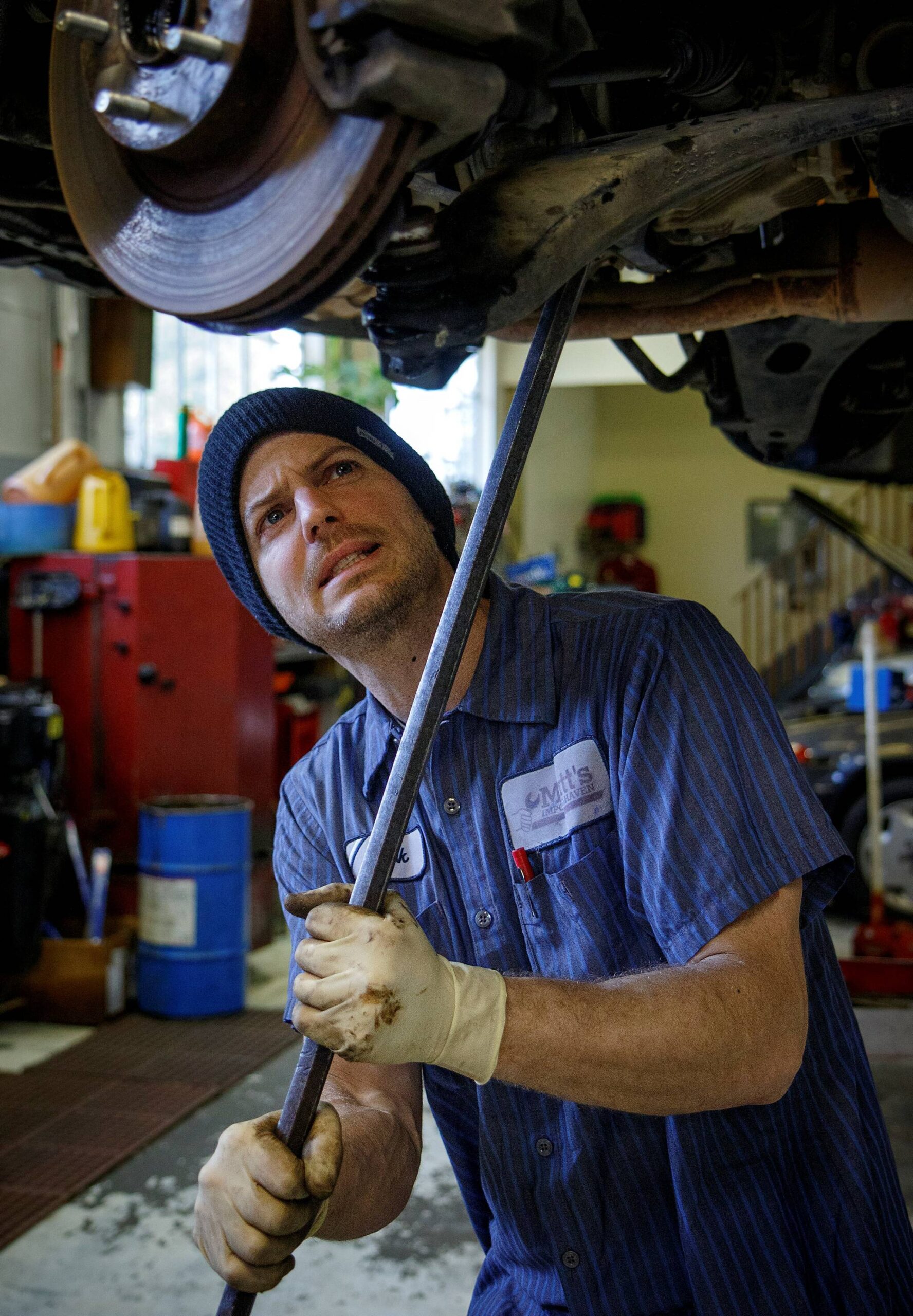 (Photo by David Welton) Senior Technician Mark Glass gets under a car to work on it.