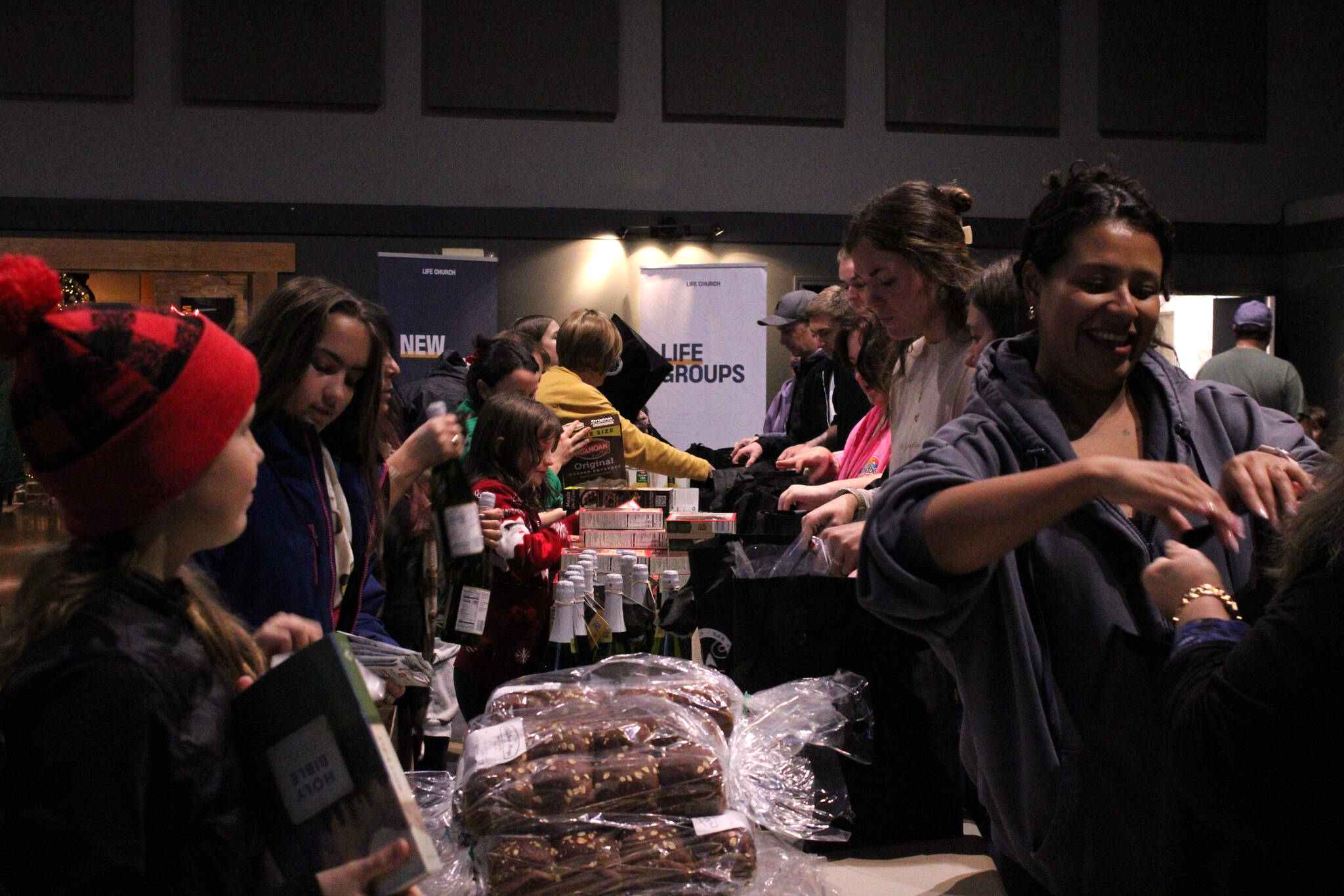 (Photo by Allyson Ballard) More than 100 volunteers gathered at Life Church Thursday evening to assemble grocery bags full of food for families in need.