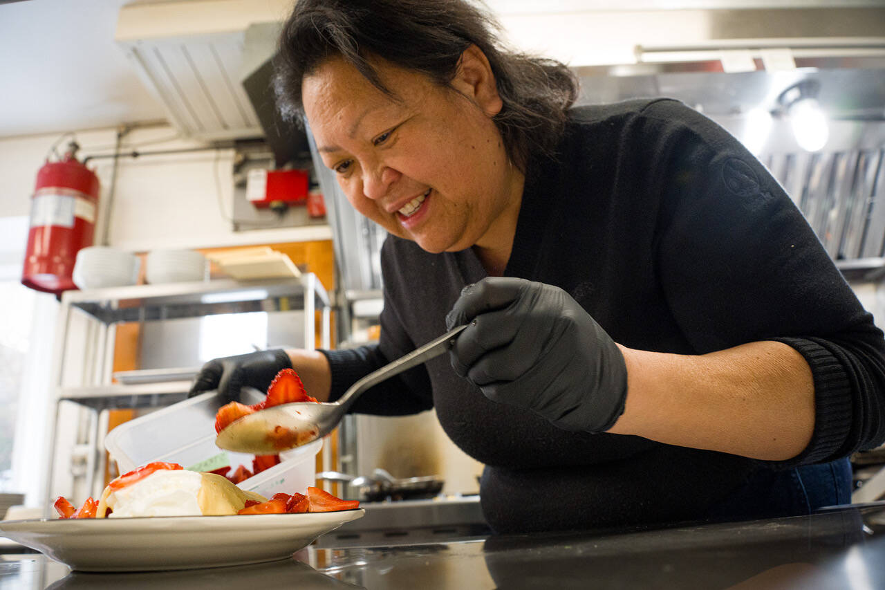 Photo by David Welton. Joan Samson, owner of Merriweather Creperie, adds strawberries to a sweet crepe.