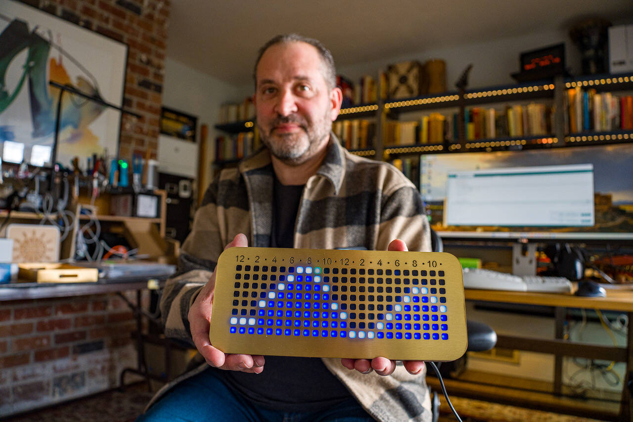 (Photo by David Welton) Dorian Garson demonstrates how the tide clock, called the NautiKron, works. The green dot represents the current hour and the waves show the tides.