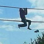 A shoeless man hangs from phone lines on North Oak Harbor Street Sunday. He told rescuers that he was trying to retrieve a pair of shoes. Photo by Robert Rizzo