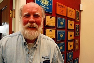 Coupeville builder Ted Clifton stands before a wall of awards. He’s now building homes so sustainable that are actually producing enough energy to power electric cars.