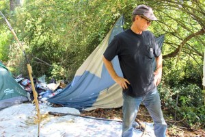 Carl Freund surveys a campsite on his property near a commercial hub in Oak Harbor. People camp on site and leave trash.