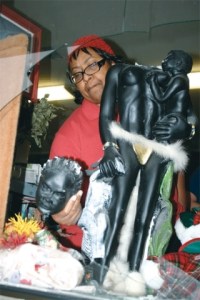 Pastor Fannie Dean reaches toward the broken thrift store window and picks up the head of a statue she has loved for 24 years. A vandal possibly motivated by hate decapitated the statue of an African mother holding a baby.