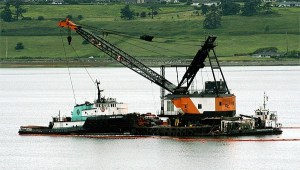 A barge with a crane was pushed into Penn Cove Monday to start work raising a crab boat that sank in mid-May.