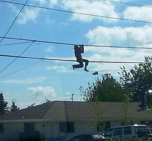 A shoeless man hangs from phone lines on North Oak Harbor Street Sunday. He told rescuers that he was trying to retrieve a pair of shoes.