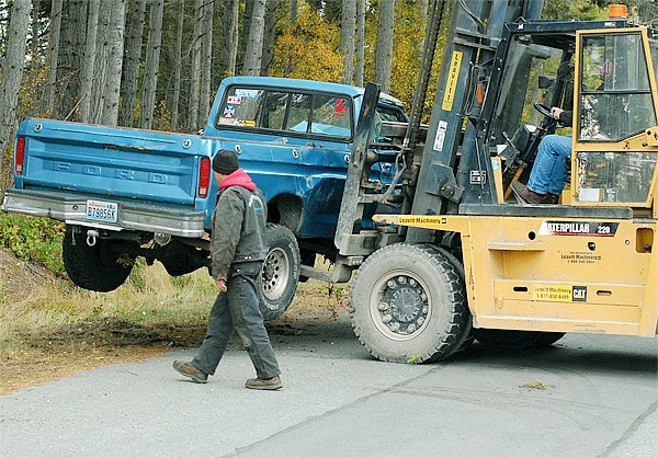Oak Harbor resident Matthew Raimondi watches as his truck is removed from the shoulder of NE Halyard Lane Wednesday by a forklift. He was in the vehicle when it rolled onto its side.
