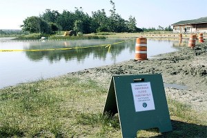 Warning signs and yellow tape are visible at the Cranberry Lake swimming area that is to help discourage people from swimming in the water. Island County Health Department officials closed the popular swimming hole at Deception Pass State Park because of high levels of E. coli bacteria caused by goose droppings.