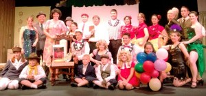 The Whidbey Playhouse cast of “Gypsy” stands with the chair they set up as part of the Julia’s Chairs movement to remember a beloved community theater stage manager.