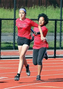 Mikhaela Cortez takes the baton from Chanel Stanley on the way to winning the seventh-grade girls 4x100 relay along with Leielle Salinger and Jenny Danielson.