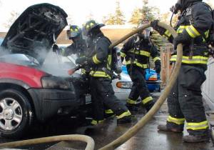 Central Whidbey Fire and Rescue firefighters hose down a vehicle on fire in Coupeville Monday