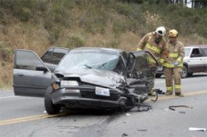 Firefighters inspect a car that was badly damaged in a accident on Highway 20