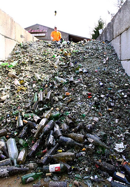 A man tosses a bottle into the pile of recycled glass at Island Recycling in Freeland.