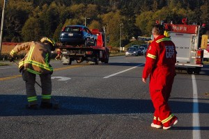 A North Whidbey Fire and Rescue firefighter sweeps up the last bit of broken glass as the vehicle it came from is towed away. The rollover accident