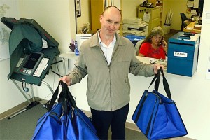 Elections Office administrator Kirk Huffer hefts bags used to transport ballots from collection boxes.
