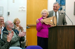 Oak Harbor Mayor Jim Slowik presents Helen Chatfield-Weeks with a plaque signifying her new status as the city’s official cheerleader before the city council and a supportive audience last week.