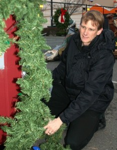 Home Depot store manager James Croft wraps garland around one of the 4-H petting zoo barns for this year’s Christmas Village. The holiday fun begins Friday