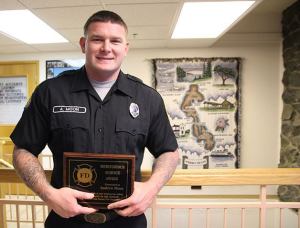 Firefighter Andrew Moon stands with his award for meritorious service for attempting to save a man’s life on his day off.