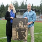Evan Thompson / The Record Jim &ldquo;Coach&rdquo; Leierer&rsquo;s daughter, Nanette Pierson (left) and community member Jon Chapman (right) stand on South Whidbey High School&rsquo;s football field next to a picture of the deceased coach. The school board unanimously approved the stadium be renamed after longtime football coach Jim &ldquo;Coach&rdquo; Leierer on Wednesday night.