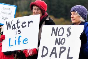 Photo by Michael B. Watkins/Whidbey News-Times                                Construction workers from WhidbeyHealth cross at State Highway 20 in Coupeville as protesters behind them protest the Dakota Access Pipeline stand outside Wells Fargo Bank in Coupeville last week. The group opposes the bank funding the pipeline project and the potential impact to the environment and native people&rsquo;s land.