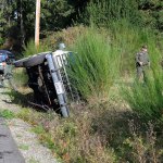 Reserve Deputy Kurt Pepper with the Island County Sheriff&rsquo;s Office speaks with a driver who rolled her Suburban onto its side Thursday on Bayview Road.