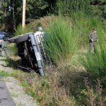 Reserve Deputy Kurt Pepper with the Island County Sheriff&rsquo;s Office speaks with a driver who rolled her Suburban onto its side Thursday on Bayview Road.