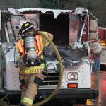 Photo by Kyle Jensen / The South Whidbey Record                                South Whidbey Fire/EMS Deputy Chief Wendy Moffatt douses the flames in a mail truck in Freeland Wednesday. A fuel leak was suspected as the cause.