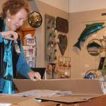 Pennie Allison Rees, a Coupeville watercolor artist, boxes up a customer&rsquo;s purchase of one of the salmon created by Oak Harbor metalworks artist Steve Nowicki Thursday, Dec. 1, at Garry Oak Gallery in Oak Harbor. Photo by Ron Newberry/Whidbey News-Times