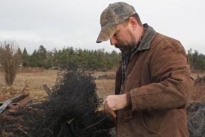 Paul Decker sorts though some tangled wiring while standing in front of a pile of debris at the Pacific Rim Institute for Environmental Stewardship outside Coupeville Wednesday, Jan. 18, 2017. Decker, a woodworker, has volunteered his time at the institute to lead a salvaging project to reduce debris and repurpose wood and other materials he finds. Photo by Ron Newberry
