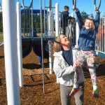Paula Seaman, principal of Hillcrest Elementary, helps first grader Milana Blatt cross the monkey bars during recess Wednesday in Oak Harbor. Photo by Daniel Warn