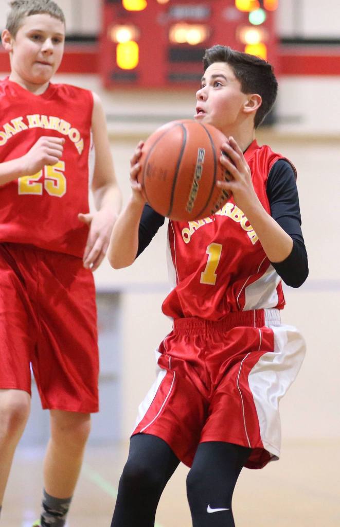 Gabe McLeod, an Oak Harbor seventh-grader, sets up for a shot Tuesday as Ethan Abbott looks on. McLeod, a team co-captain, finished with 2 points, 6 assists and 5 rebounds. Co-captain Abbott recorded 14 points, 19 rebounds and 3 blocks.(Photo by John Fisken)