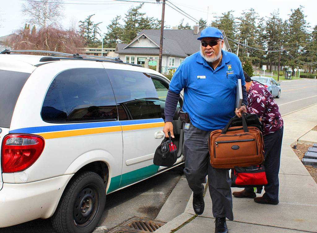 At a shift change in Coupeville, Island Transit driver Otis Jenkins hustles to start his afternoon duty as driver Tito Gutierrez ends his day. Photo by Patricia Guthrie/Whidbey News-Times