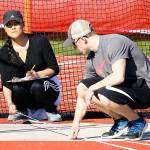 Eileen Stone, left, and Dalton Martin help out with the discus in Thursday&rsquo;s meet. (Photo by John Fisken
