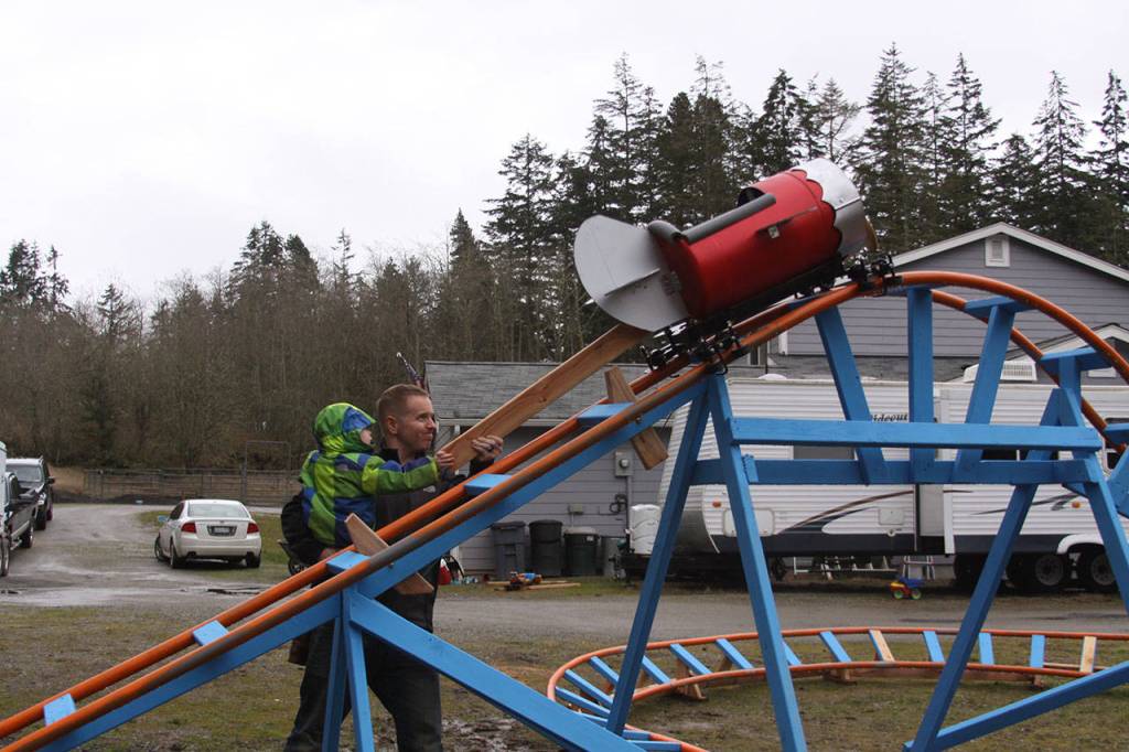 Scott Brazelton, with help from his son Wyatt, gets the roller coaster cart in position to launch at his property in Oak Harbor Wednesday, March 1, 2017. Brazelton, a Navy pilot, built a roller coaster from scratch for his 3-year-old son. Photo by Ron Newberry/Whidbey News-Times