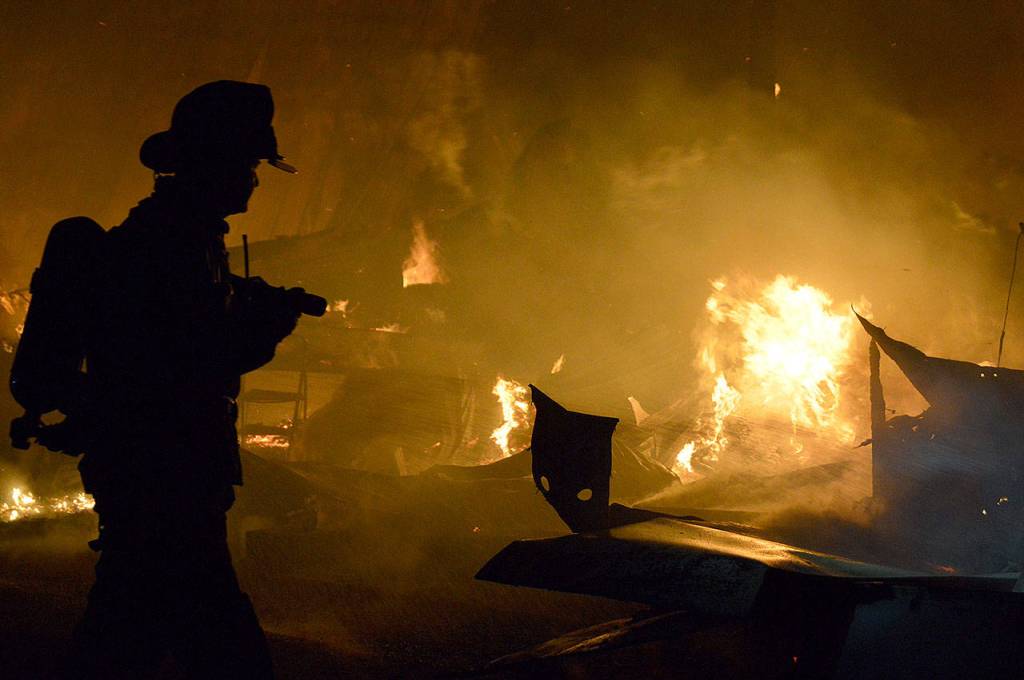 A firefighter battles a blaze that knocked out a Central Whidbey icon Monday night, March 6, 2017. The fire destroyed the historic Smith Barn at Willowood Farm in Coupeville. Photo by Megan Hansen/Whidbey News-Times