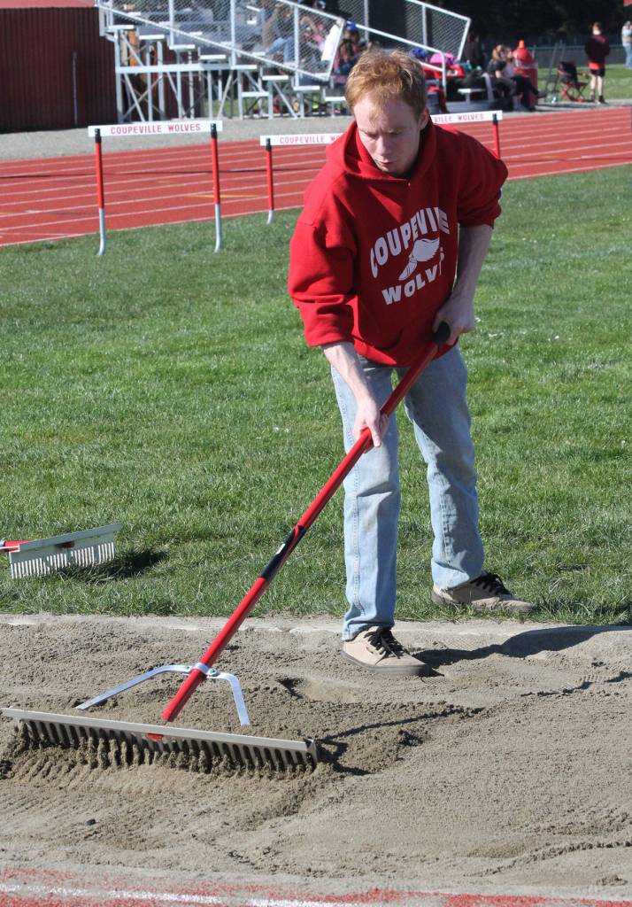 Jesse Hester rakes up the triple jump pit. (Photo by Jim Waller/Whidbey News-Times)
