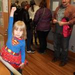 Katrina Daggett, Supergirl, strikes a pose at Oak Harbor Library&rsquo;s comicon, which neared 400 attendees Saturday in it&rsquo;s first year. Her father, Steve Daggett, looks on with pride from behind.                                Photo by Daniel Warn/Whidbey News-Times