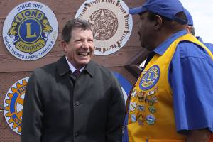 Oak Harbor Mayor Bob Severns, left, visits with Oak Harbor Lion James House in front of the city&rsquo;s welcome sign that also features the emblems of the community&rsquo;s service organizations. The Oak Harbor Lions celebrated the centennial anniversary of their parent club, Lions Clubs International, by installing a new emblem. Photo by Ron Newberry/Whidbey News-Times