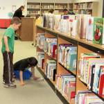 Casey Cook, left, and a fellow Crescent Harbor Elementary student peruse the books at the school&rsquo;s library. According to school librarian Bill Montross, 98 percent of the library&rsquo;s approximate 14,000 offerings are included in the Accelerated Reader program. Photo provided
