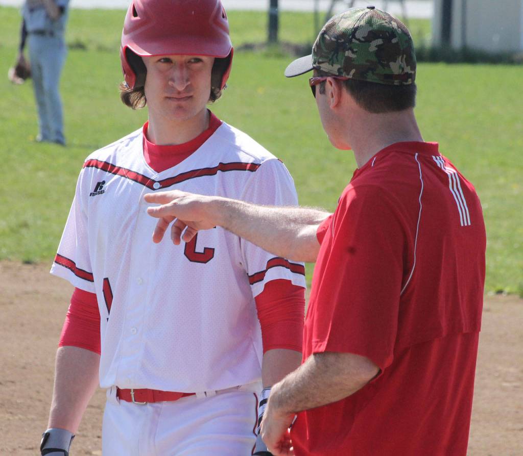 Runner Clay Reilly, left, and assistant coach Scott Hillborn discuss strategy during a break in the first inning. (Photo by Jim Waller/Whidbey News-Times)