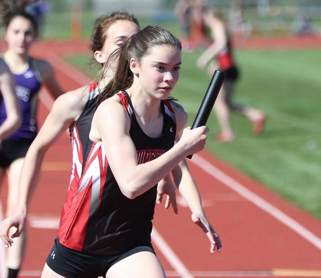 Maya Toomey-Stout takes a handoff from Mallory Kortuem as the Wolves win the 4x200 relay. (Photo by John Fisken)