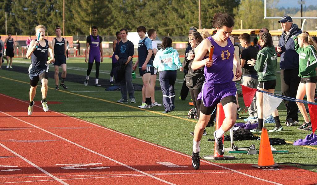 Miguel Guzman crosses the finish line for the winning Oak Harbor 4x400 relay team. (Photo by John Fisken)