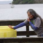 Port of Coupeville Harbormaster Long Bechard talks on the phone while pushing a container full of oil spill containment booms at the Coupeville Wharf Friday afternoon. Even though only about two or three quarters of hydraulic steering fluid leaked from the burst hose of a vessel that docked at the wharf, the sheen spread out hundreds of feet as can be seen in the background. Photo by Ron Newberry/Whidbey News-Times
