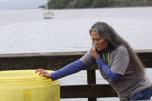 Port of Coupeville Harbormaster Long Bechard talks on the phone while pushing a container full of oil spill containment booms at the Coupeville Wharf Friday afternoon. Even though only about two or three quarters of hydraulic steering fluid leaked from the burst hose of a vessel that docked at the wharf, the sheen spread out hundreds of feet as can be seen in the background. Photo by Ron Newberry/Whidbey News-Times