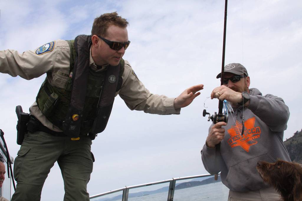 Taylor Kimball, enforcement officer with Washington Department of Fish and Wildlife, checks a lingcod angler&rsquo;s hooks for barbs, which are not allowed in saltwater, Wednesday, May 10, 2017, while out on patrol. Photo by Ron Newberry/Whidbey News-Times