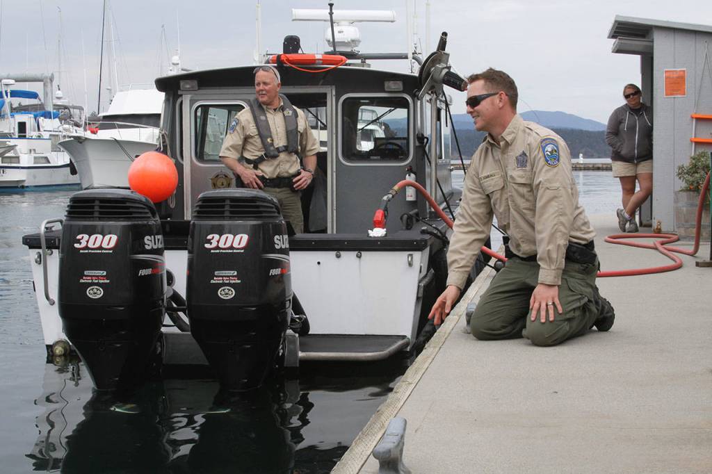 Ralph Downes, left, enforcement officer with Washington Department of Fish and Wildlife, watches as fellow officer Taylor Kimball tries to catch the attention of Popeye the harbor seal at Friday Harbor Wednesday, May 10, 2017. The enforcement officers stopped in Friday Harbor for gas. Photo by Ron Newberry/Whidbey News-Times