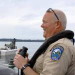 Ralph Downes, enforcement officer with Washington Department of Fish and Wildlife and resident of Central Whidbey, scans boaters across the water near San Juan Island. Downes has been doing his job for 26 years. &lsquo;We always find neat stuff,&rsquo; he said. &lsquo;Sometimes, it&rsquo;s a little more unusual and off the wall.&rsquo; Photo by Ron Newberry/Whidbey News-Times