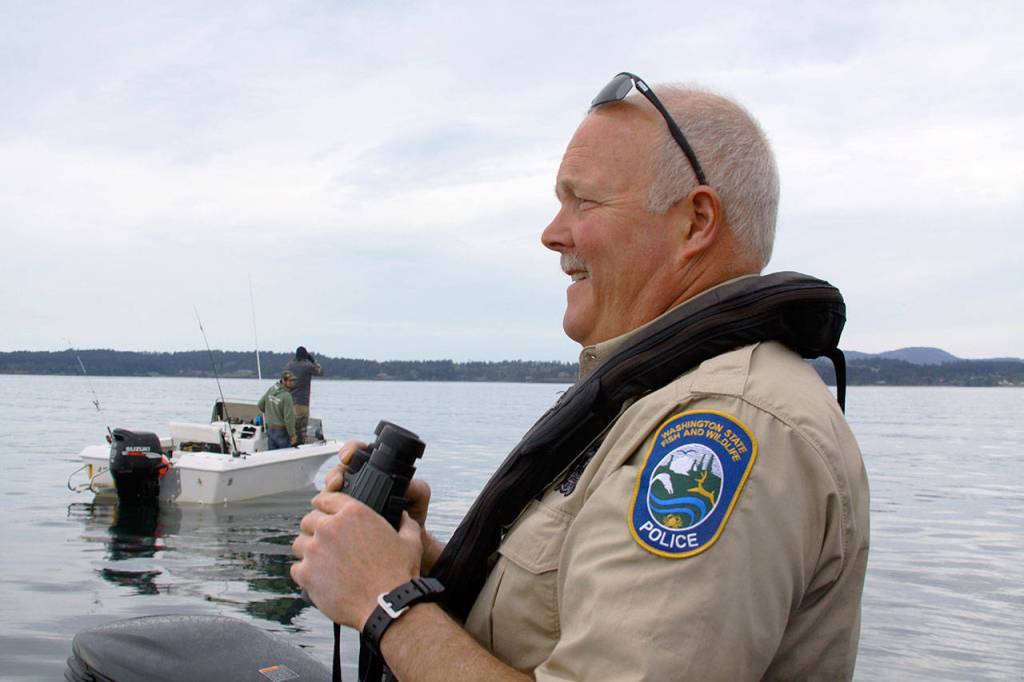 Ralph Downes, enforcement officer with Washington Department of Fish and Wildlife and resident of Central Whidbey, scans boaters across the water near San Juan Island. Downes has been doing his job for 26 years. &lsquo;We always find neat stuff,&rsquo; he said. &lsquo;Sometimes, it&rsquo;s a little more unusual and off the wall.&rsquo; Photo by Ron Newberry/Whidbey News-Times