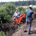 Craig Holmquist uses an excavator Monday, May 22, 2017 to dig a hole for a new vault toilet that will be installed in June near the office of Ebey&rsquo;s Landing National Historical Reserve in Coupeville. Carl Sholin, an archaeologist with the National Park Service, monitors the dig. The Reserve will be busy with several projects this summer as it braces for an increasing number of visitors. Photo by Ron Newberry/Whidbey News-Times