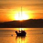 A solitary sailboat greets the dawn sun May 22 in the waters around Coupeville to kick off a sunny spring day. Photo by Timothy J. Mumford‎